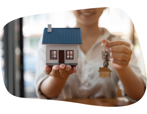Mulher segurando e mostrando uma chave e uma casa miniatura nas mãos