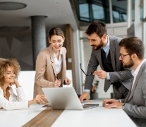 Trabalhadores ao redor da mesa olhando para um notebook