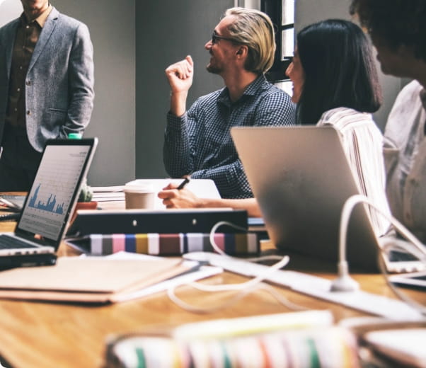 Pessoas sentadas à mesa de reunião, observando uma apresentação.