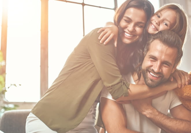 Banner Principal Pai e mãe felizes com sua filha se abrançando.