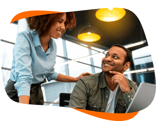 Homem e mulher se olham em frente a um notebook